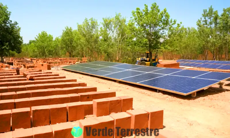 Obra moderna en construcción con ladrillos ecológicos, rodeada de un entorno verde y trabajadores activos, bajo un cielo azul con paneles solares