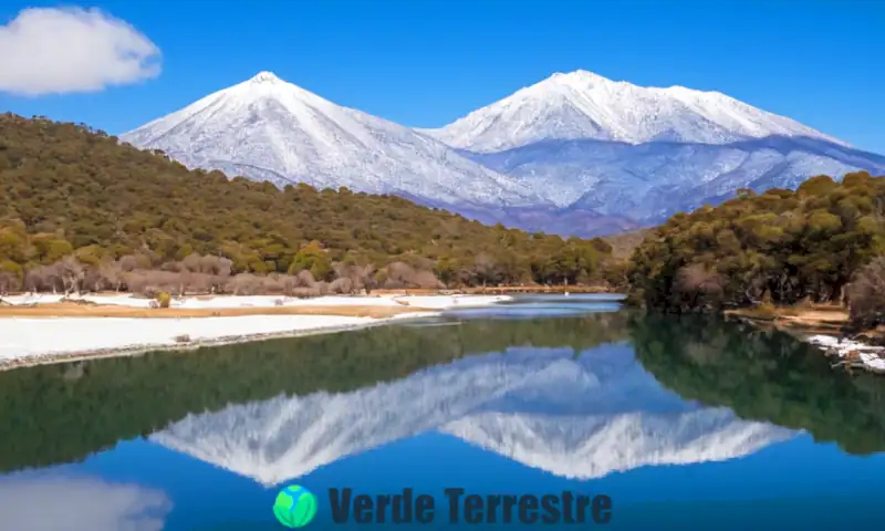 Paisaje invernal de Toluca con montañas nevadas, un lago congelado, bosques brumosos y arquitectura colonial en tonos azules y blancos