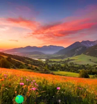 Amanecer vibrante sobre un paisaje sereno con montañas y un prado de flores silvestres