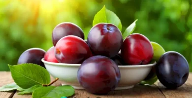 Varias variedades de ciruelas de colores diferentes sobre una mesa de madera rústica